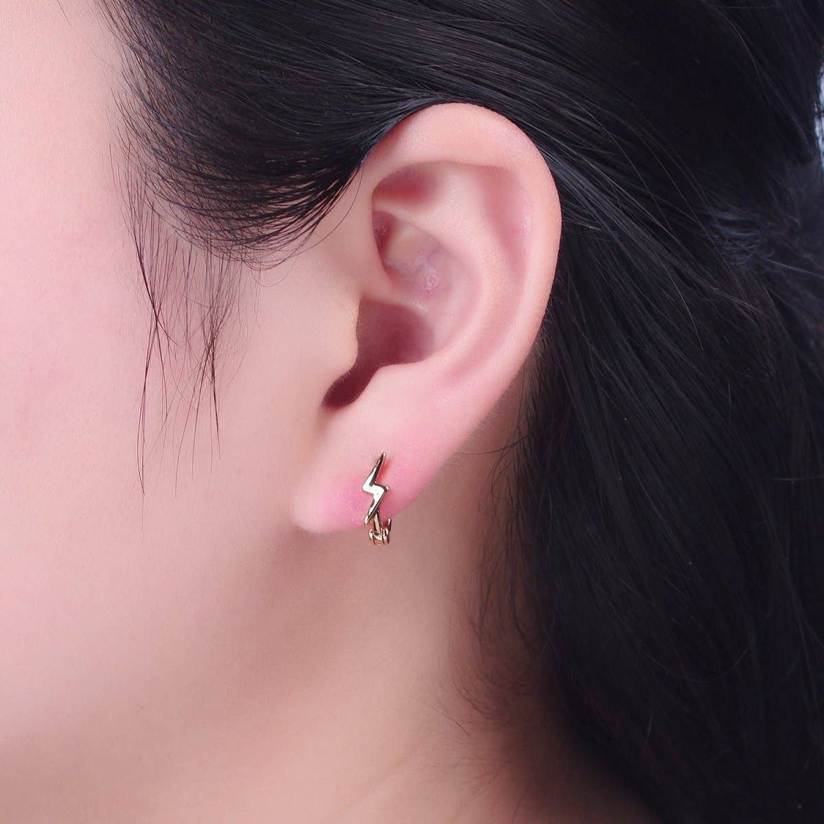 Woman wearing gold lightning bolt huggie hoop earring – close-up lifestyle shot showing fit on ear