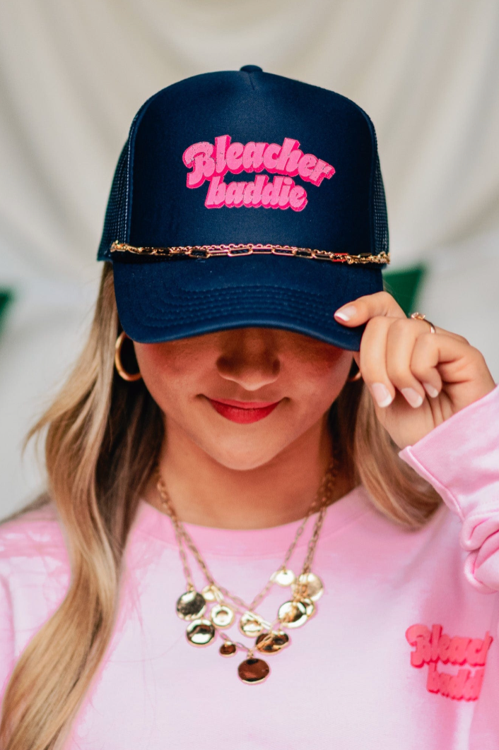 Bleacher Baddie navy foam trucker hat with pink bubble lettering and gold hat chain