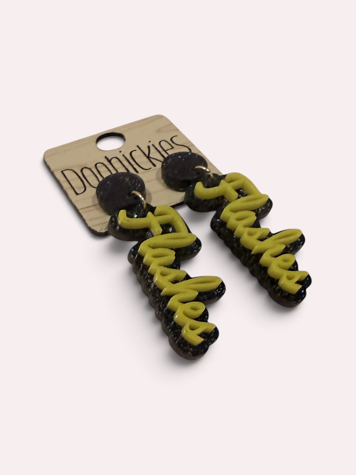 Angled view of gold and navy glitter Flashes script earrings for Florence game day