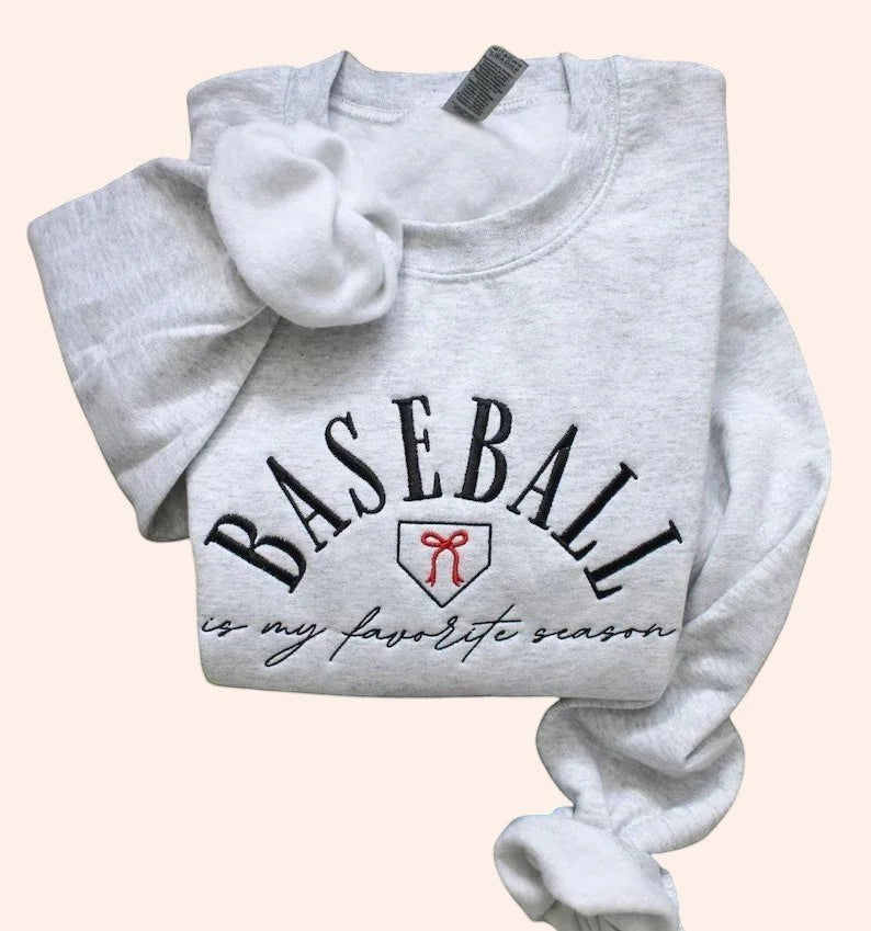 Bleacher Babe light grey embroidered crewneck sweatshirt with "BASEBALL is my favorite season" text and baseball home plate graphic.