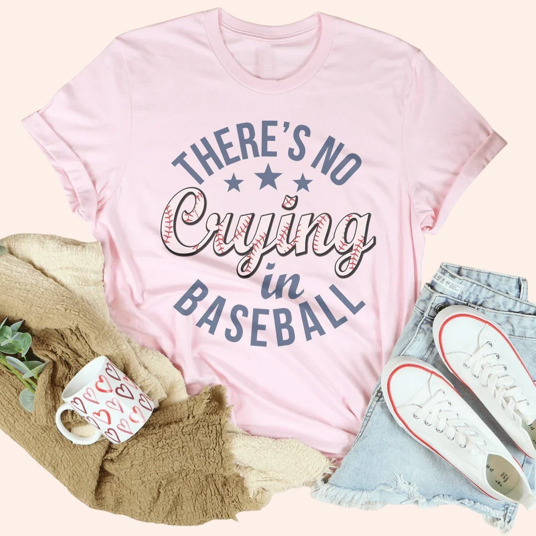 Bleacher Babe pink graphic tee with "There's No Crying in Baseball" text in blue and baseball stitching detail.