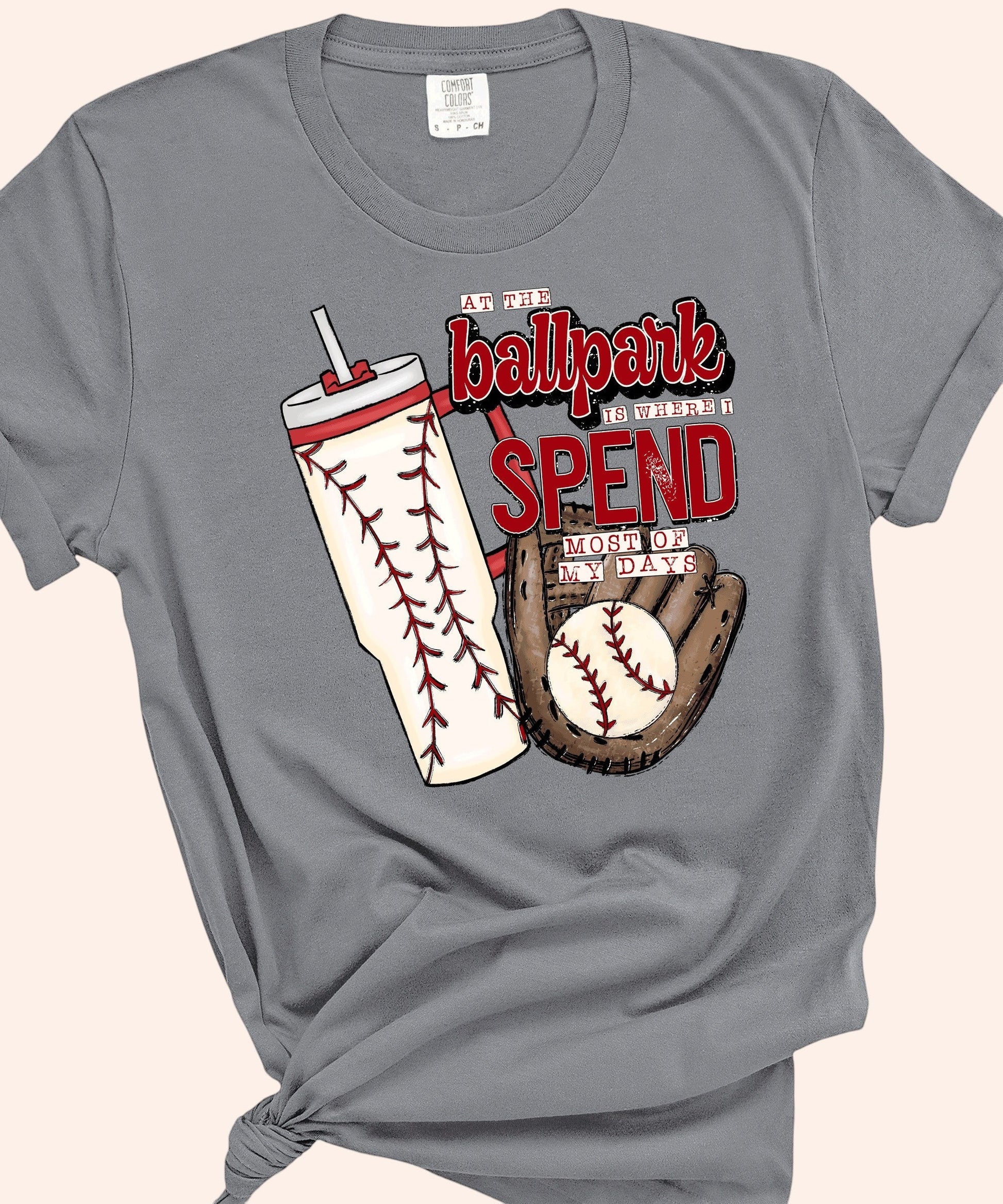 Bleacher Babe grey graphic tee with baseball glove, ball, and tumbler. "At the ballpark is where I spend most of my days" text.