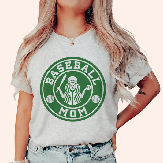 Bleacher Babe light grey t-shirt with green "Baseball Mom" graphic featuring a woman with flowing hair holding a baseball bat and ball.