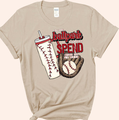Bleacher Babe baseball mom graphic tee in tan, featuring a baseball glove, ball, and tumbler with baseball stitching.