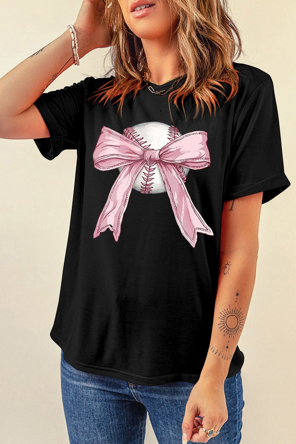 Bleacher Babe black baseball tee with a pink bow graphic on a baseball. Short sleeves, crew neck.