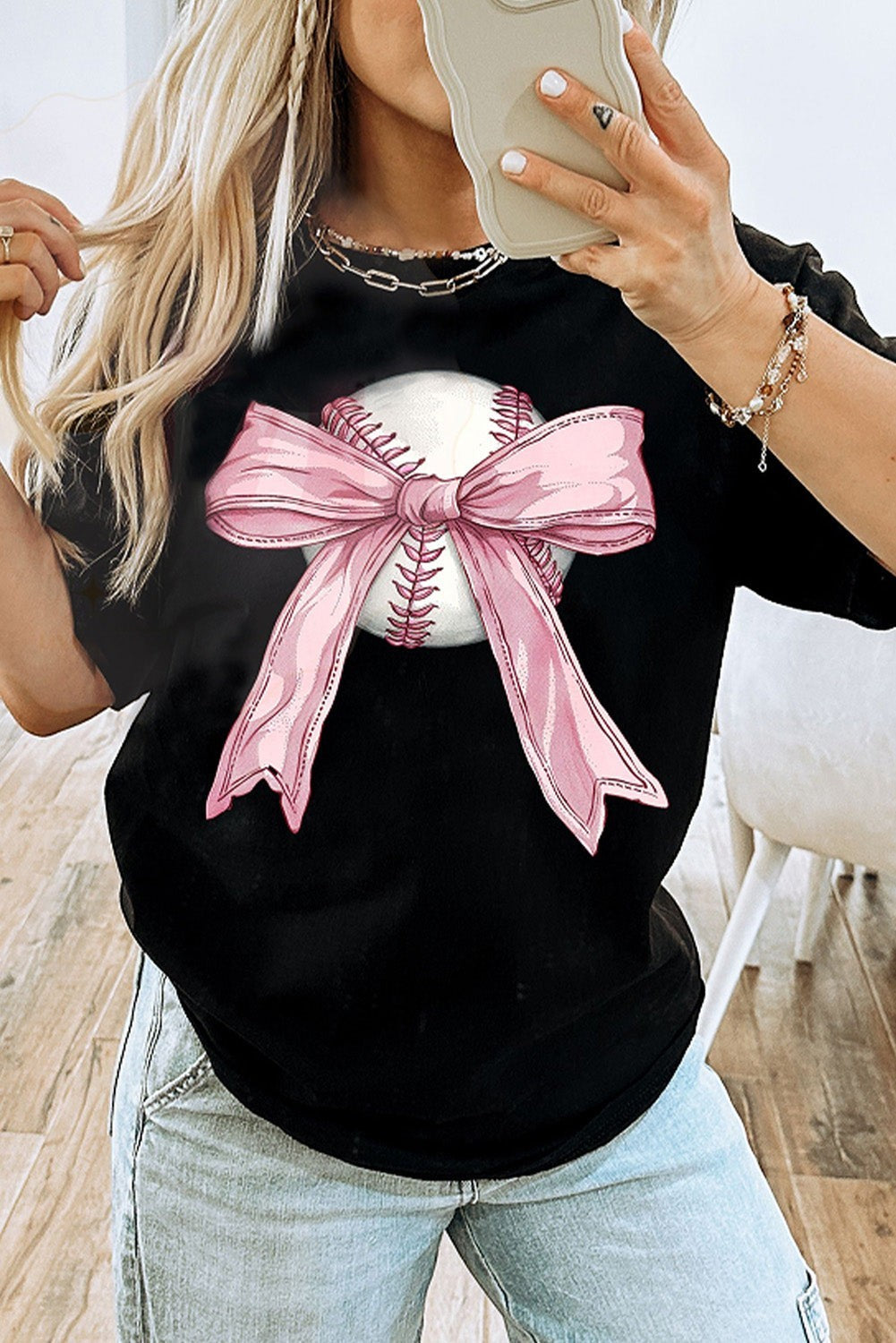 Bleacher Babe black baseball tee with a graphic of a baseball wrapped in a pink bow.