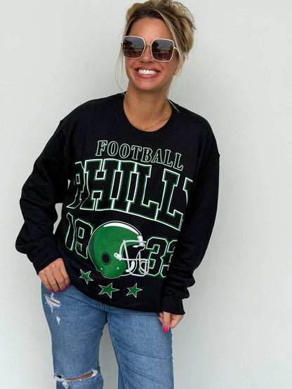 Bleacher Babe black unisex sweatshirt with green and white vintage football screen print worn by a smiling woman