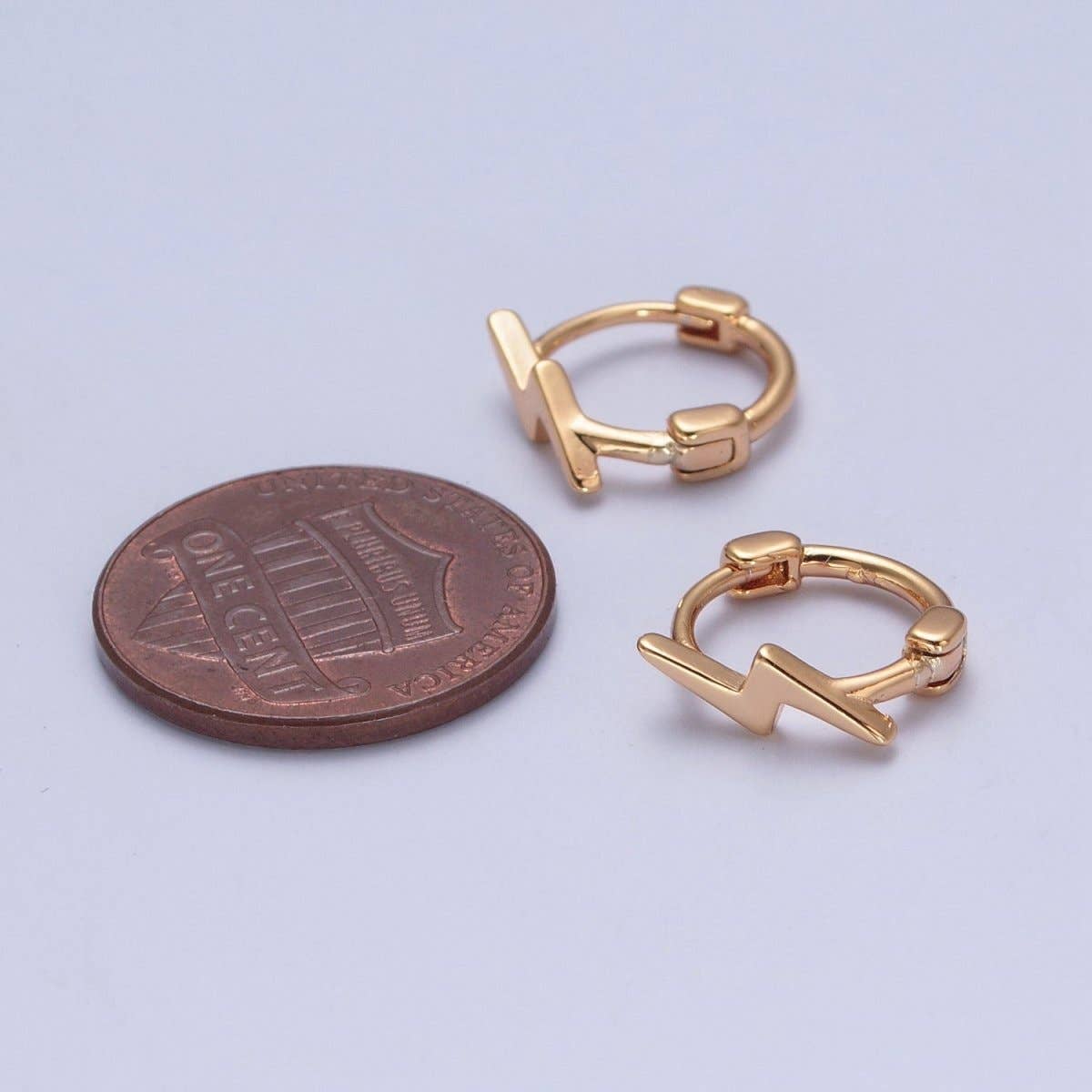 Gold lightning bolt huggie hoop earrings size comparison next to a penny – 11.9mm small hoop earrings